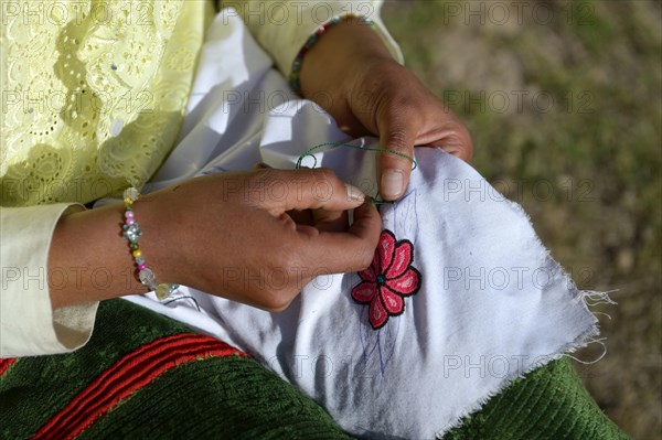 Young woman embroidering a cloth with traditional patterns