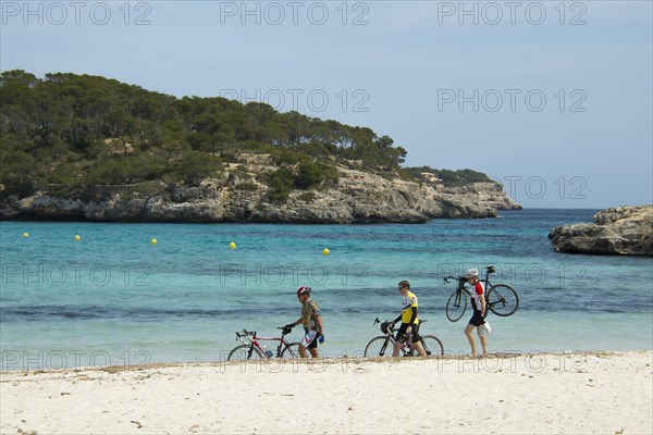 Racing cyclists walking along the beach