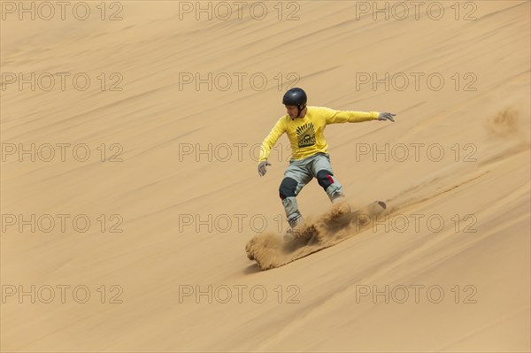 Sand boarding in the dunes of the Namib Desert