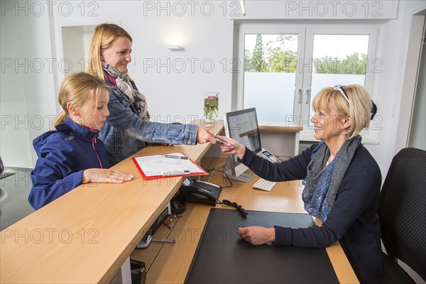 Patients filling in a form at the reception of a dental office