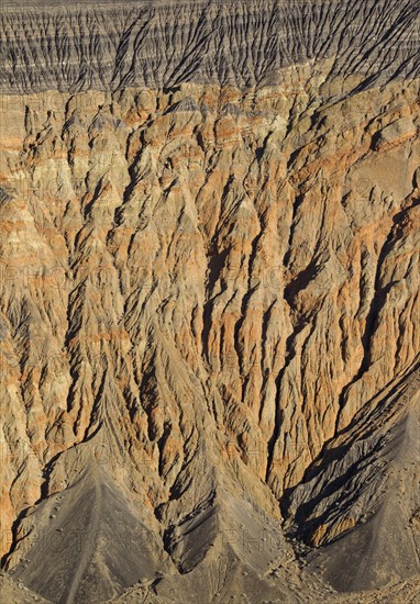 Exposed fissured bedrock of orange-colored conglomerate on the crater wall of Ubehebe Crater