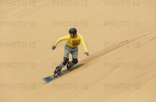 Sand boarding in the dunes of the Namib Desert