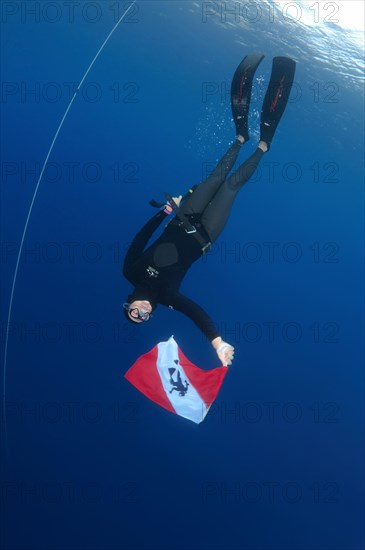Freediver holds a diver down flag