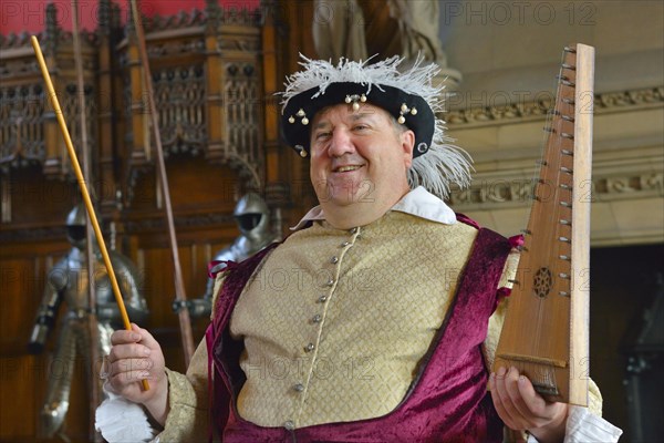 Musician in period costume performing on a medieval psaltery