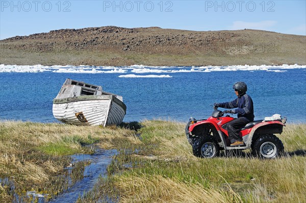 Man of the Inuit people riding a quad bike