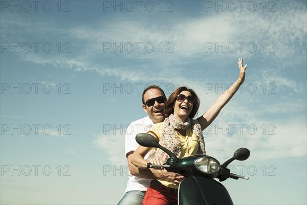 Smiling couple driving with the scooter