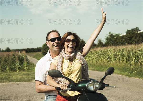 Smiling couple driving with the scooter