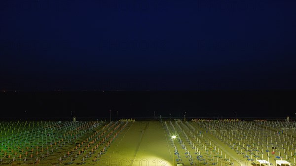 View of a beach with sunshades and sun beds at midnight