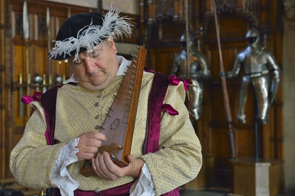 Musician in period costume performing on a medieval psaltery