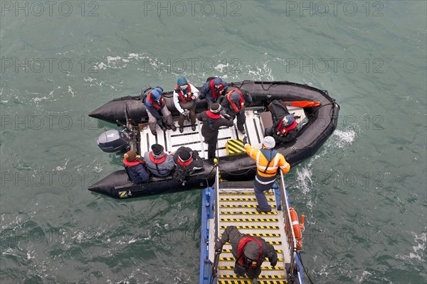 Tourists being helped out of an inflatable boat