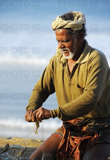 Fisherman taking small fish out of the net