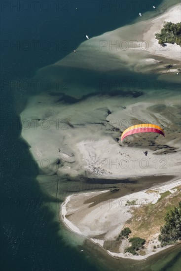 Paraglider over the Maggia river delta with naturally formed water and rocks terrain