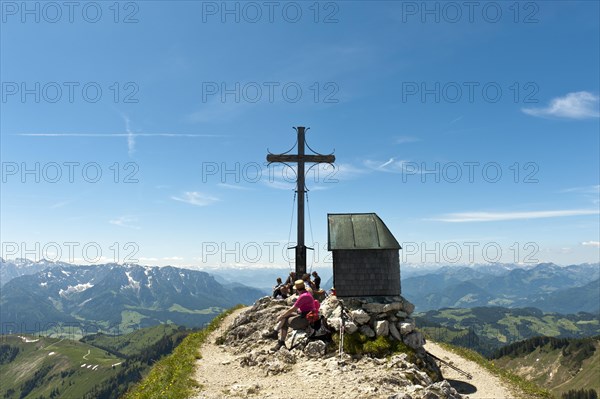 Mountain climber at the summit cross with a small chapel on Geigelstein Mountain