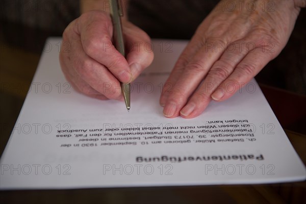 Hands of a 82-year-old woman signing a living will