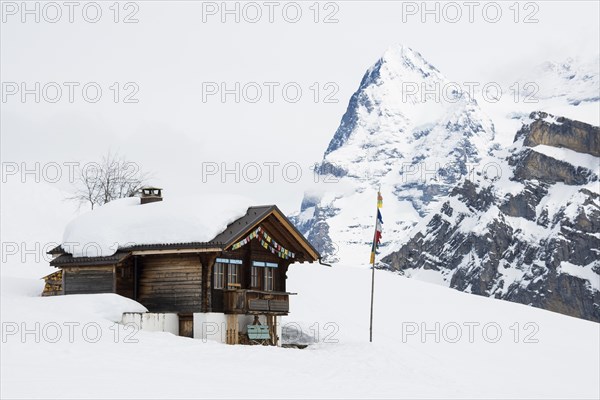 Old log cabin and the Bernese Oberland with Mt Eiger in winter