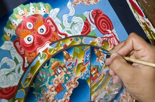 Artist painting a colourful Thangka in an art school