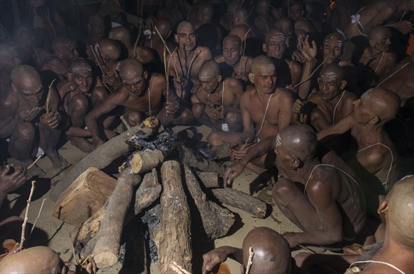 Sitting around a bonfire and chanting mantras as part of the initiation of new sadhus