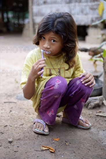 Girl brushing her teeth outside a house