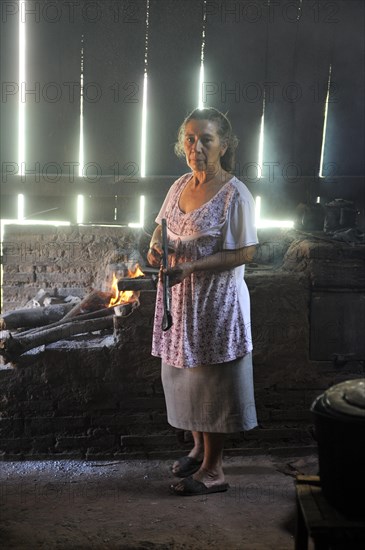 Elderly woman in a basic kitchen cooking on an open fire