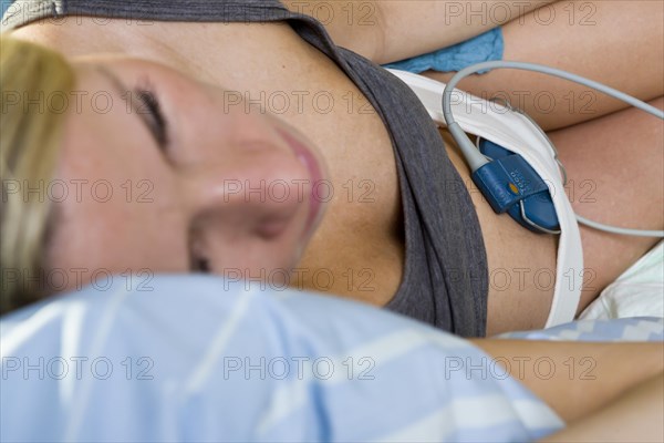 Pregnant woman resting on a delivery bed during childbirth connected to a cardiotocography or CTG