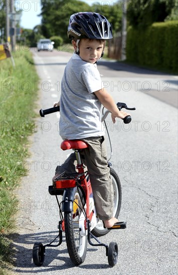 Boy riding a bicycle with training wheels