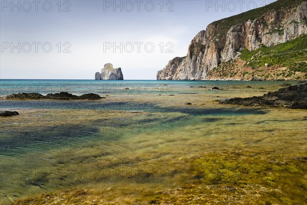 Spiaggia di Masua bay with the Pan di Zuccherof rock island in the sea