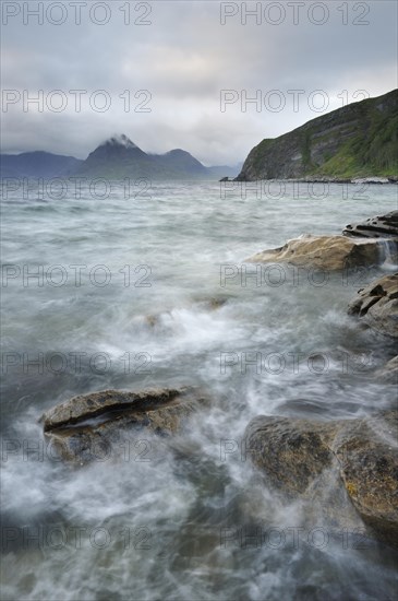 Mountains shrouded with clouds on a rocky seashore