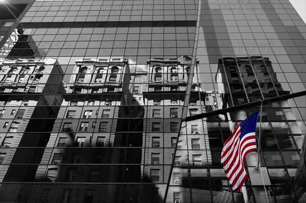 Houses are reflected in the glass facade of a skyscraper