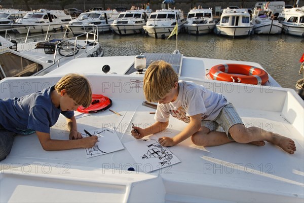 Two boys drawing on a houseboat in a harbour on the Canal du Midi