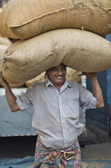 Man carrying two bags filled with spices on his head