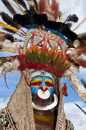 Man in a colourfully decorated costume with face paint at the traditional sing-sing gathering
