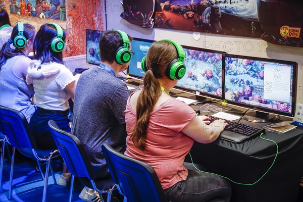 Visitors playing a computer game in front of screens