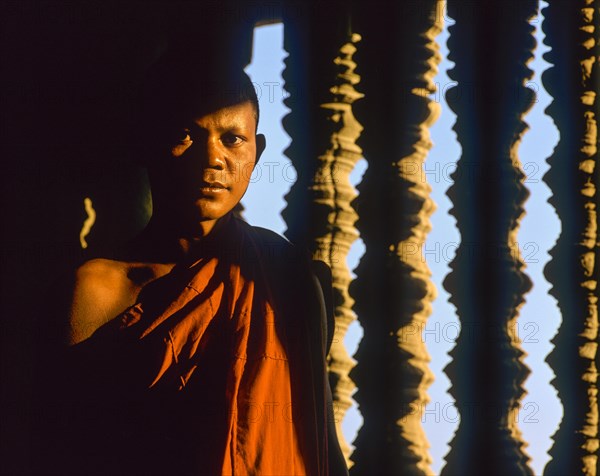 Buddhist monk in front of a baluster window in the temple of Angkor Wat