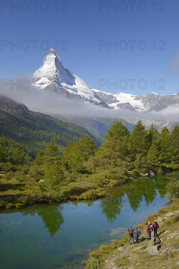 Hikers taking photographs of the Matterhorn with Lake Grindjisee in the foreground
