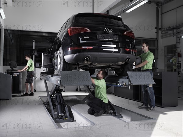 Workers assembling panels to track wheel alignments