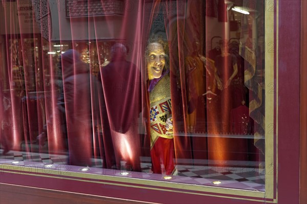 Wax figure looking through a gap in the curtain