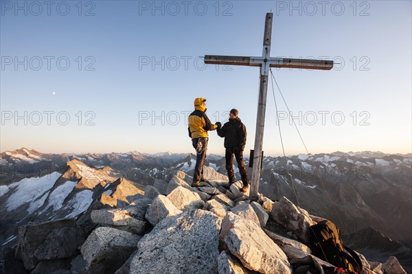 Mountain climbers on the summit cross of Reichenspitze Mountain