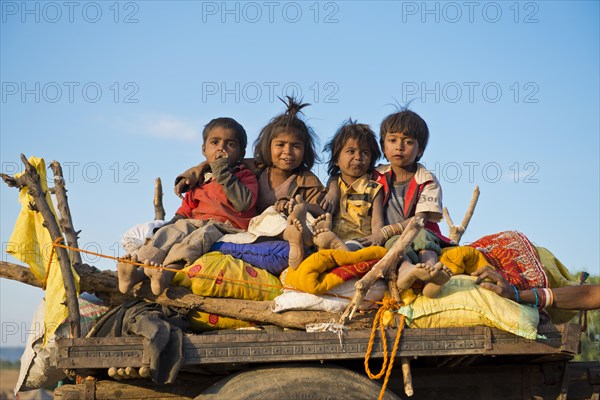 Four children sitting on a camel cart