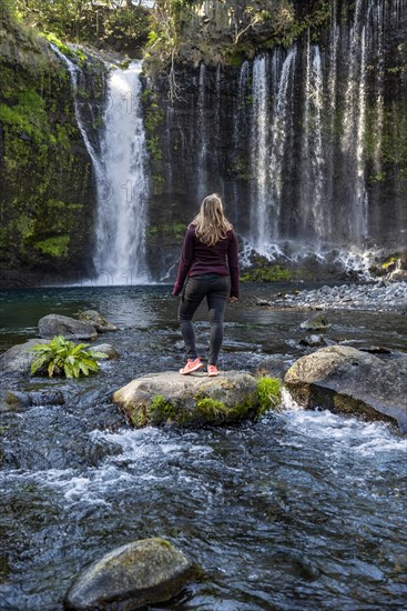 Young woman standing on a stone in a river