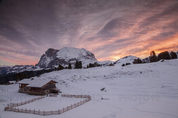 Sunrise over Mt Plattkofel and a mountain hut in winter