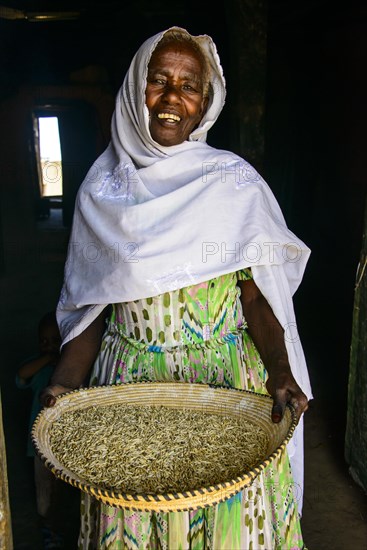 Friendly old woman standing with a basket of corn