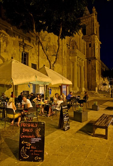 Tourists sitting in an outdoor restaurant at St. John's Co-Cathedral