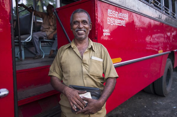 Bus driver in front of a red bus