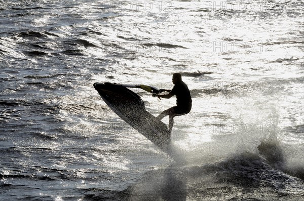 Man riding a water scooter in backlight