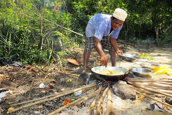 Man at cooking fire on the beach of Ilots Choizil