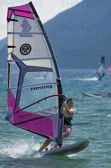 Female windsurfer surfing across the water on her board