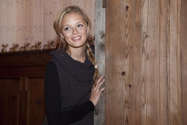 Smiling young woman leaning against a old door