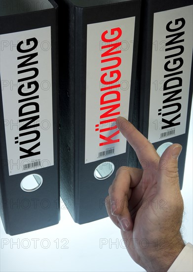 Hand pointing to a file folder labeled 'Kuendigung'