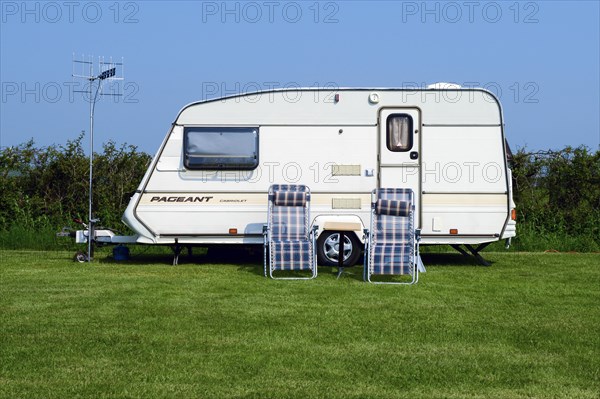 Caravan with deck chairs and a TV antenna