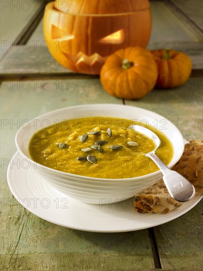 Pumpkin and bacon soup with a traditional Halloween pumpkin with a carved face